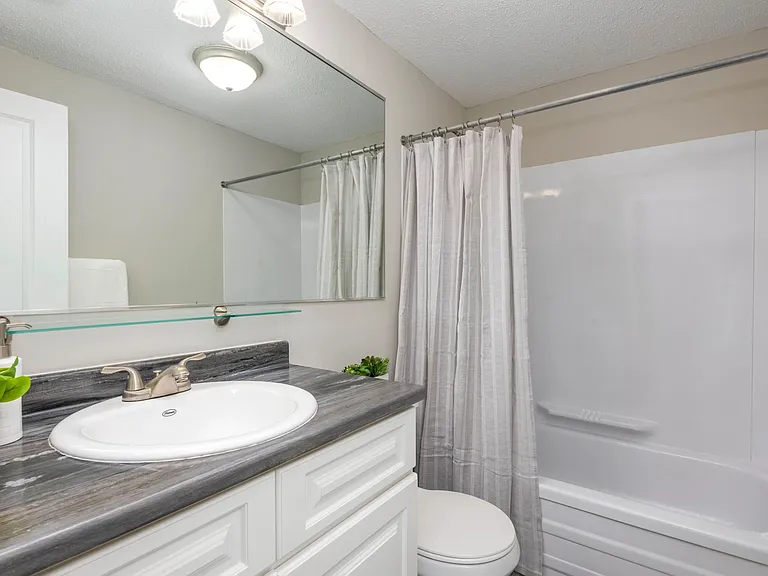Experience timeless bathroom design with classic features including an oversized mirror and ample vanity lighting.