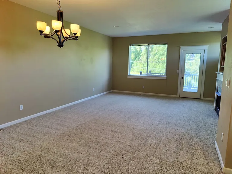 Open and spacious living room with large window and the door to the deck and backyard.