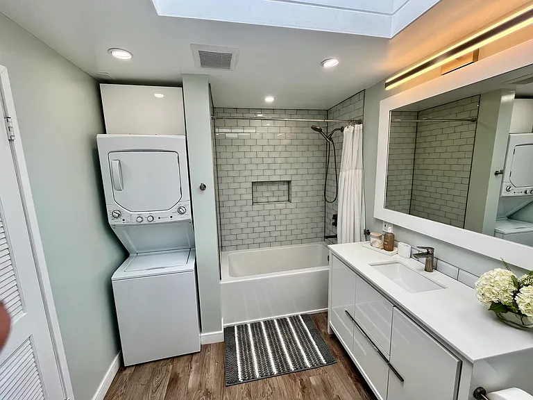 In unit washer-dryer in bathroom nook with storage above.