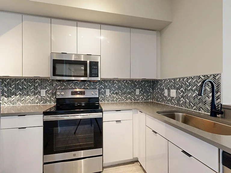 Apartment Kitchen with Quartz counter tops and Wood-Style Flooring.