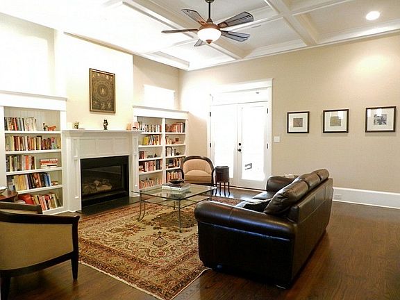 Living room features tall 10' coffered ceiling, gas fireplace and wall of built-in bookcases