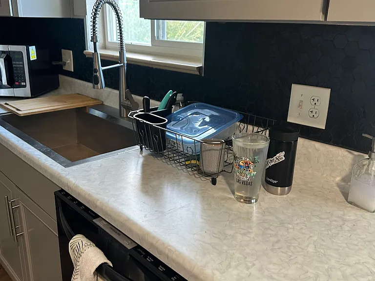 Kitchen workspace with a deep undermount sink, pull-down spring faucet, ample counter space, and a window over the sink.