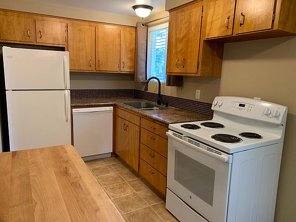Kitchen with tile backsplash, dishwasher, refrigerator, range and kitchen cart