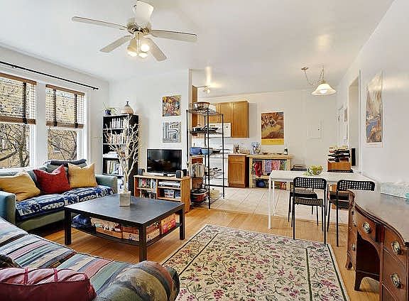 Spacious sunny living room flowing into eat in kitchen, ceiling fan, hardwood floors.