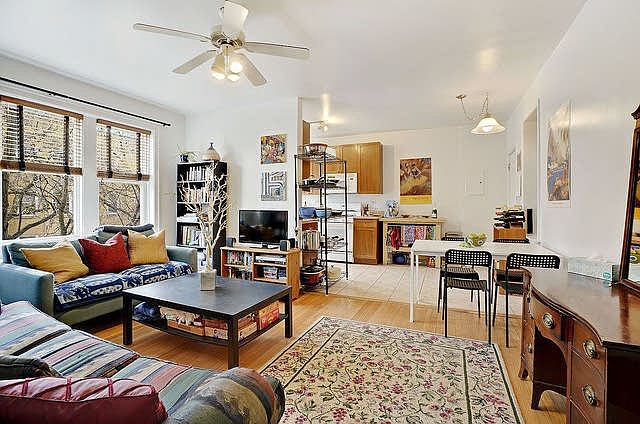 Spacious sunny living room flowing into eat in kitchen, ceiling fan, hardwood floors.