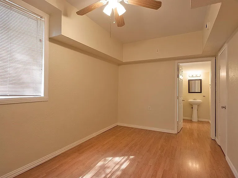 A cozy bedroom with a window featuring hardwood floors and a ceiling fan, perfect for keeping cool and comfortable.