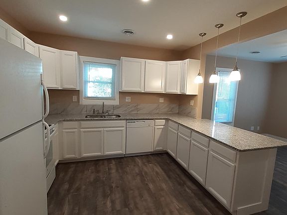 Kitchen with granite countertops, tile backsplash, plentiful cabinet space, dishwasher, and new appliances.