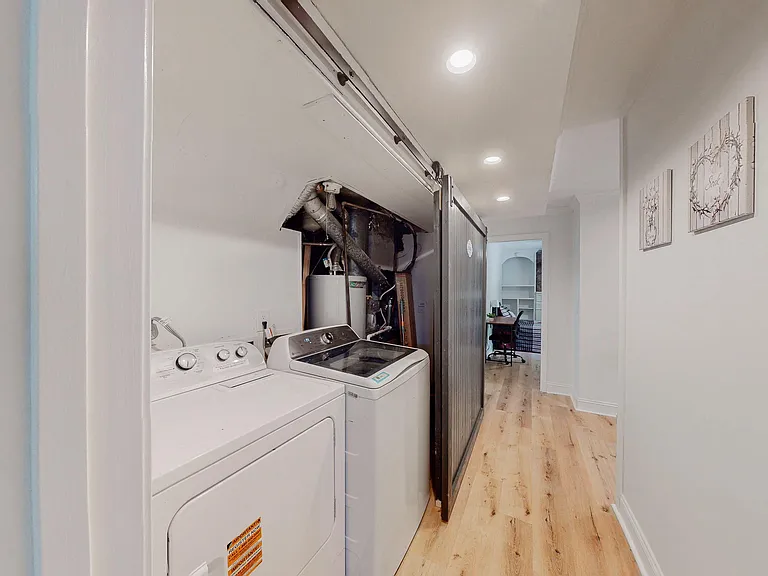 Dedicated laundry nook with full-size washer and dryer, recessed lighting, and easy access off the main hallway.