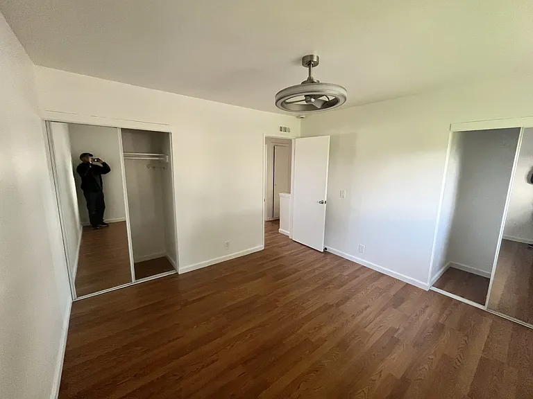 primary bedroom, 2 mirrored closets, laminate flooring, ceiling fan/light.