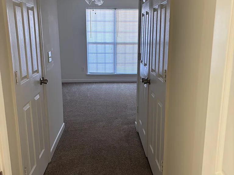 Bedroom Hallway that leads into the bathroom. Double doors are a laundry closet. Single door in hallway is a walk in closet.