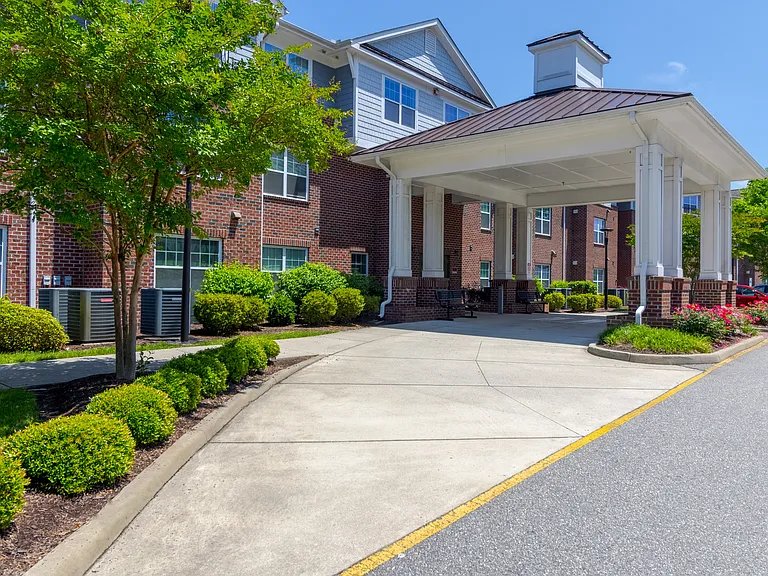 Curved entry driveway lined with greenery and trees, leading to the welcoming covered entrance at Snowden Senior Apartments.