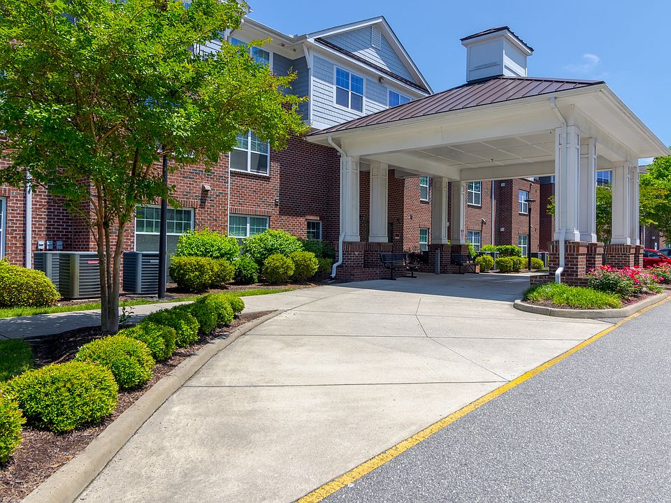 Curved entry driveway lined with greenery and trees, leading to the welcoming covered entrance at Snowden Senior Apartments.
