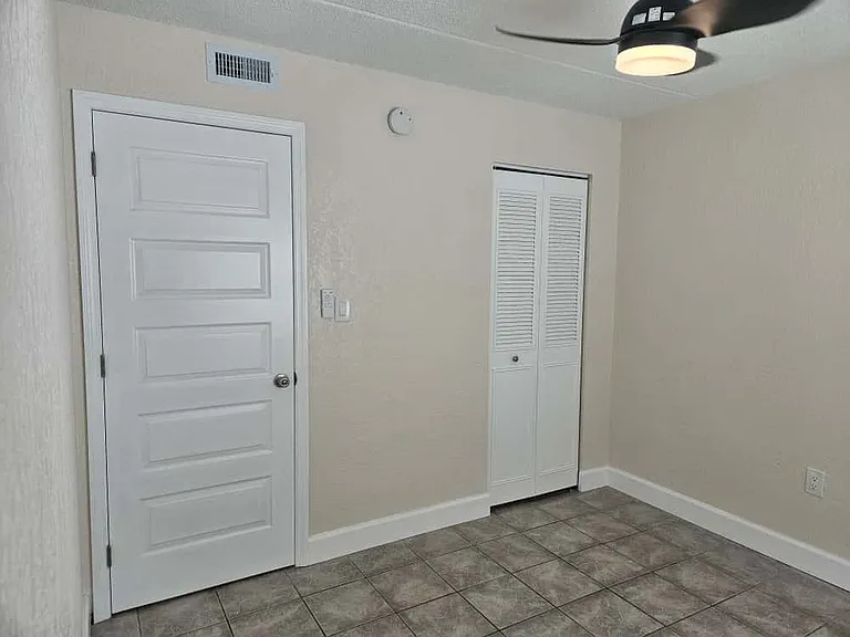Bright second bedroom with window providing natural light and a standard-size closet
