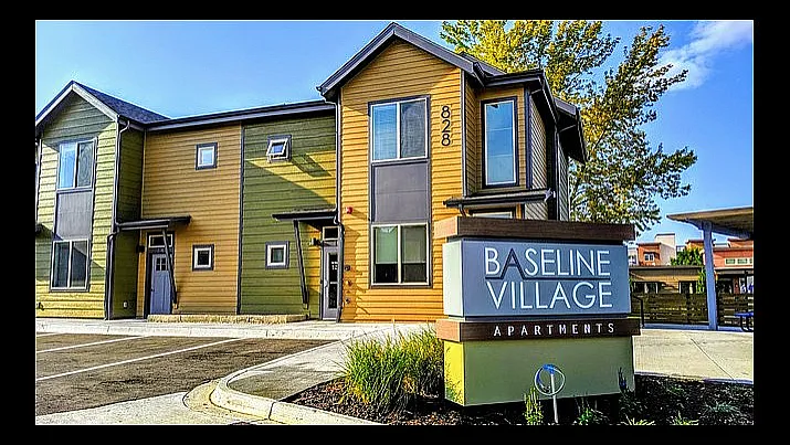 Charming multi-color facade of Baseline Village Apartments surrounded by lush greenery, showcasing modern design and welcoming atmosphere.