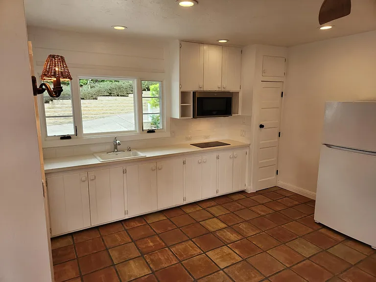 Large open kitchen with classic cabinetry, slide out drawers, and pantry with 5 paneled door. Crank out windows for fresh air.