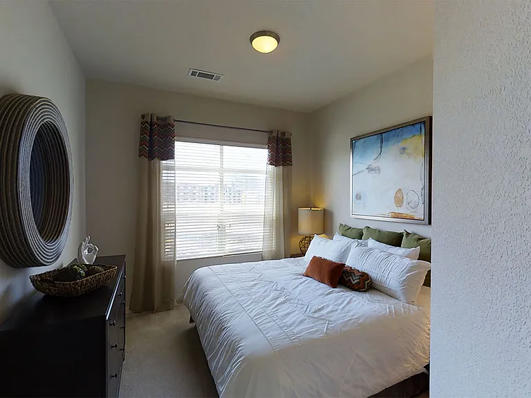 Spacious apartment bedroom with plush carpet flooring.