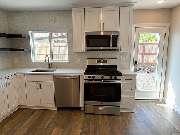 Kitchen with cabinetry and rustic floating shelving.