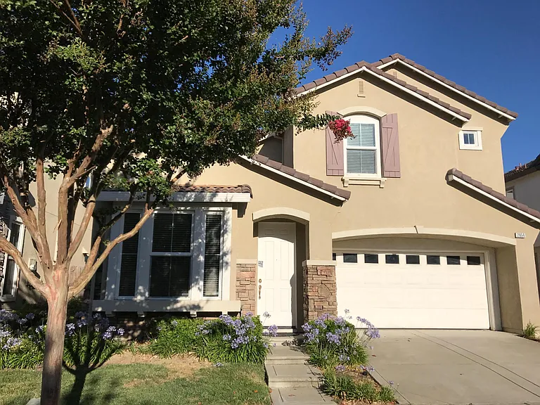 Front view: A gated walkway on the left offers backyard access and trash bins storage. Above the garage is a bedroom with a Jack & Jill bath, featuring the small window on the right.