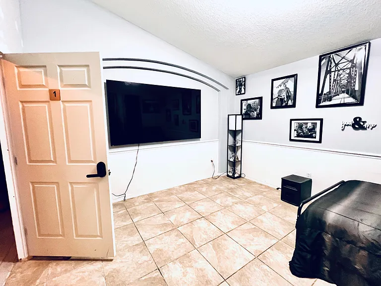 Bedroom lounge area with wall-mounted TV, tiled floors, and space for seatingideal for relaxing or streaming.