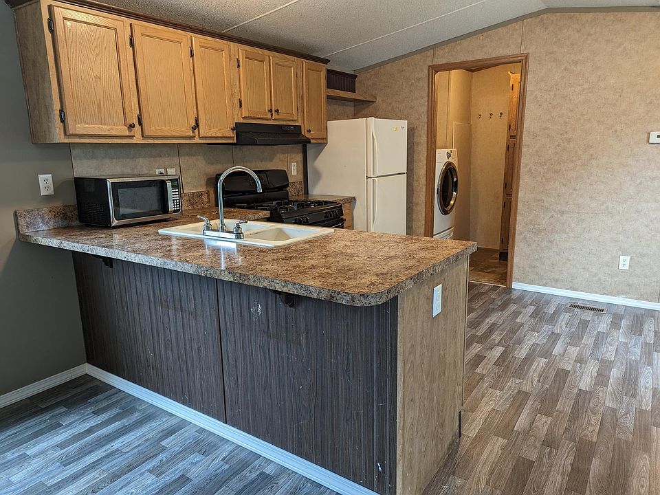 Open concept kitchen with laundry room behind kitchen with cabinets.