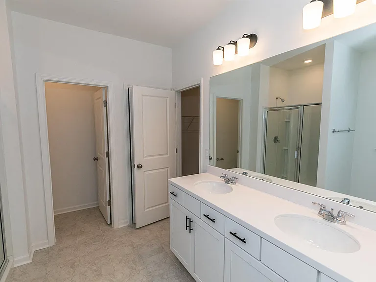 Primary bathroom with double vanity, walk-in shower and walk-in closet.