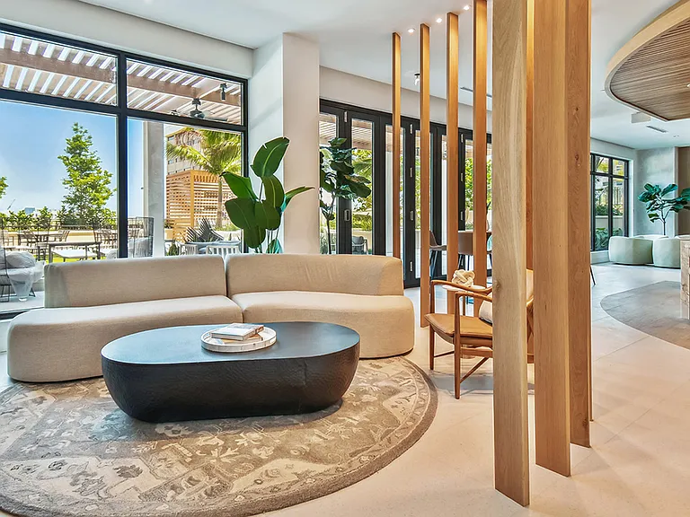 Griffis West Palm apartments resident lounge with plush couch, coffee table with books, and elegant decor.