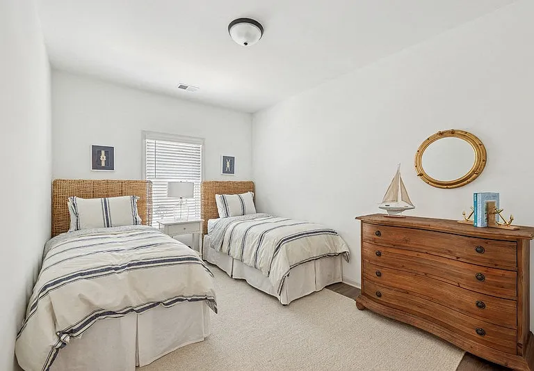 Charming third bedroom featuring two twin beds and a nightstand adorned with a sailboat accent.