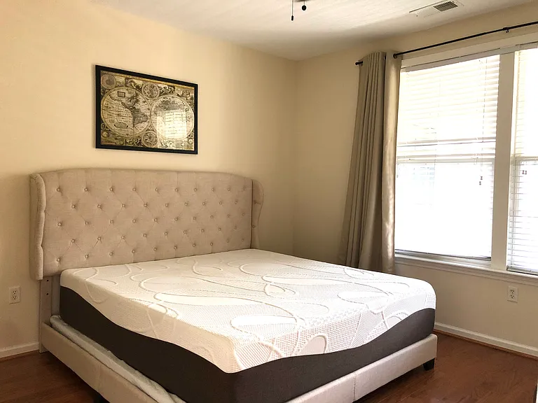 Master bedroom furnished with a king-size bed and a dresser with a mirror