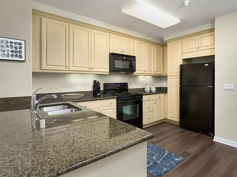 Classic Package I kitchen with black appliances, brown speckled granite, oak cabinetry, and hard surface flooring
