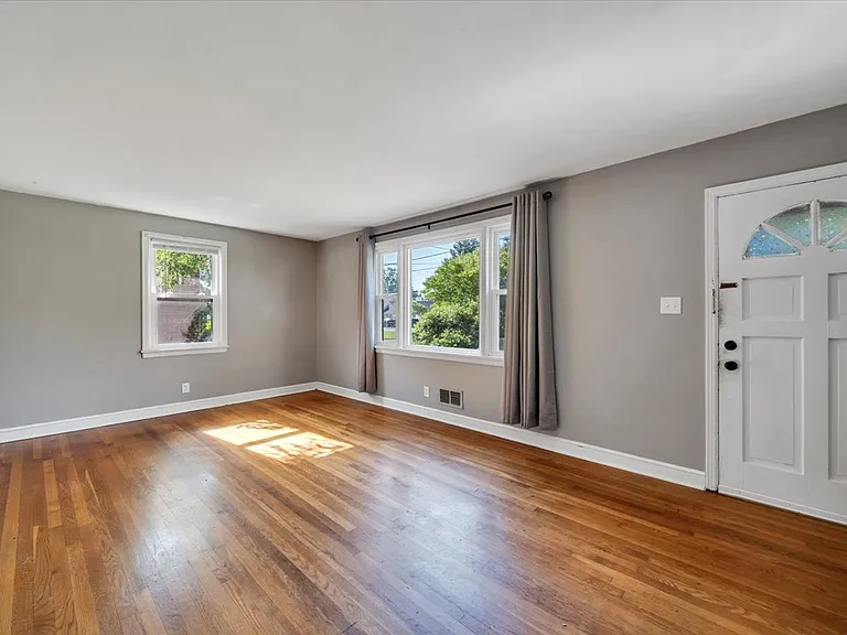 Living Room w/ Hardwood Floors and Bay Window! NEW Black Matte Curtain Rods Installed by Landlord!
