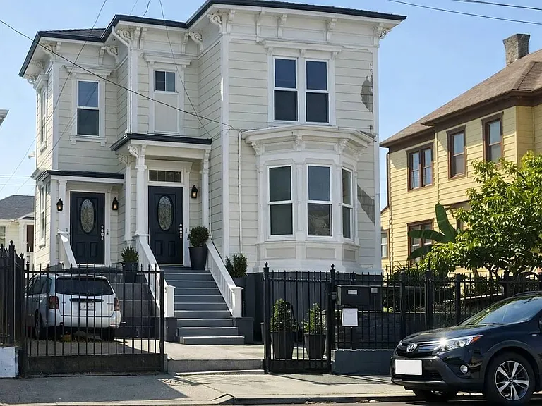 Well-maintained multi-unit exterior with separate front entries, bay windows, and gated front area.
