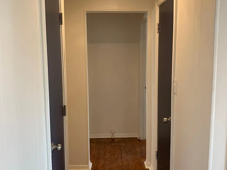 Hallway with storage closet to the right with HVAC and bath room to the left. Two bedrooms at the end of hallway.