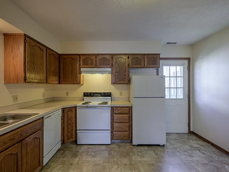 Brown cabinets and white appliances in a kitchen at Gretna Oaks.
