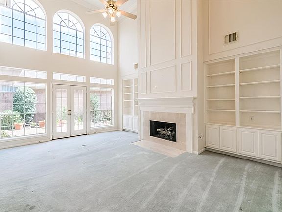 Customized built in cabinets and shelves encase an oversized fireplace and is surrounded with Italian tile.