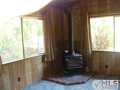 living room with wood burning stove  wood paneled walls