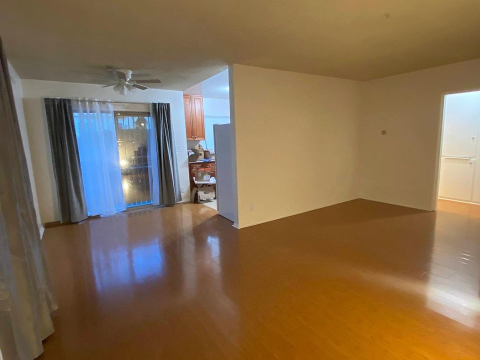 Very large open floor plan entryway, living and dining room with wood floors. Ceiling fan in dining area.