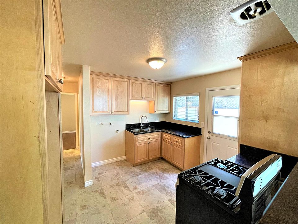 Kitchen with tile flooring, maple cabinets, granite counters and new stainless range and washer hookups. Hall leads to bedrooms and bathroom.