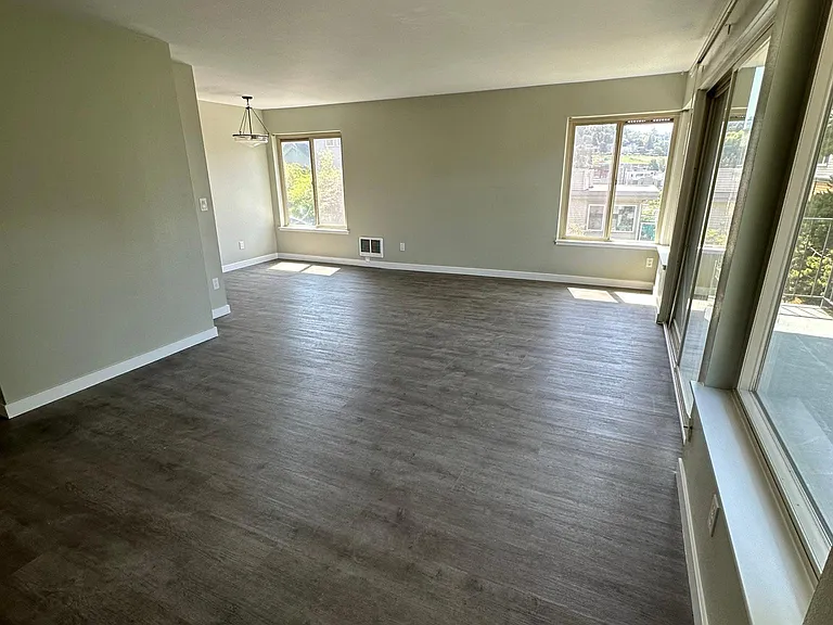 Large living room with balcony and dining room area. West facing balcony and windows and south facing windows in the living and dining area.