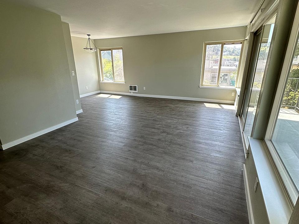 Large living room with balcony and dining room area. West facing balcony and windows and south facing windows in the living and dining area.