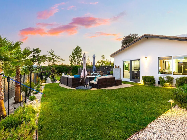 Secluded backyard oasis with green lawn, outdoor entertaining space,and tranquil evening views,