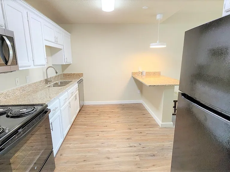 Granite countertops with undercounter sink and full size refrigerator.