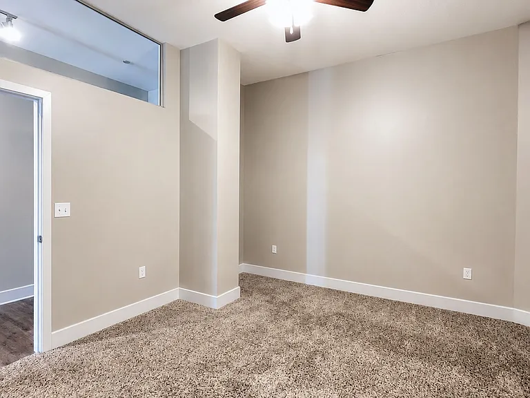 Step into a spacious bedroom at Heer's Luxury Living, featuring plush carpeting and modern ceiling fans. This inviting space offers comfort and style for your lifestyle. Don't miss out. Schedule a tour today!