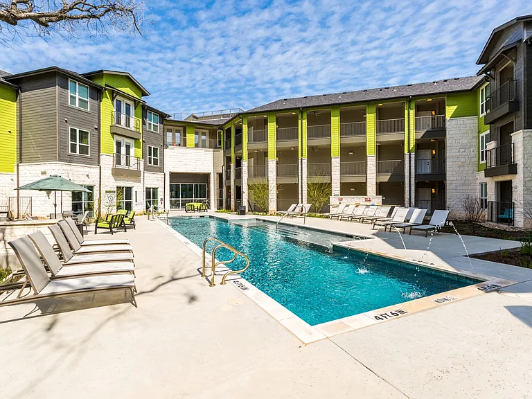 Pool with poolside lounge seating and umbrella shaded tables