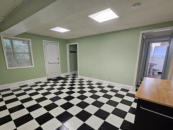 View of living area showing private entrance, front hall to bedroom and rear hallway to bathroom, which is outside rear bedroom door. A storage room is located to the right of the bathroom. Rolling cart is provided and can be stored if not wanted.