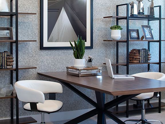 A modern and minimalist home office space with a wooden desk, black metal frame, and various decorat