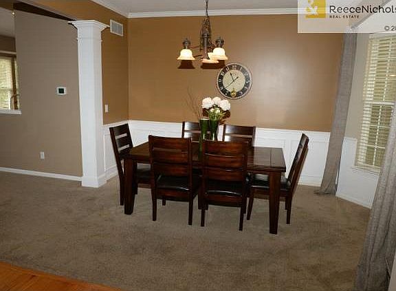 Carpeted formal dining room with a bay window.