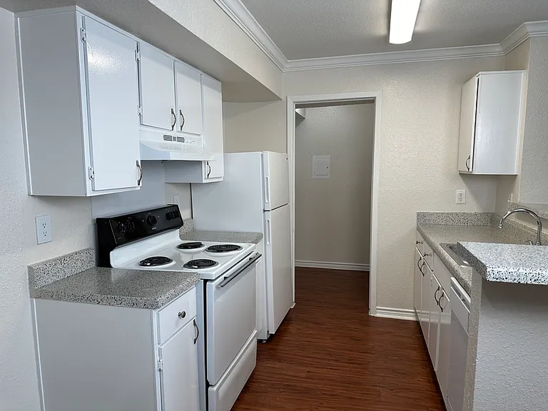 Modern kitchen with sleek white cabinetry, elegant countertops, and wood-style flooring. Modern kitchen with sleek white cabinetry, elegant countertops, and wood-style flooring.