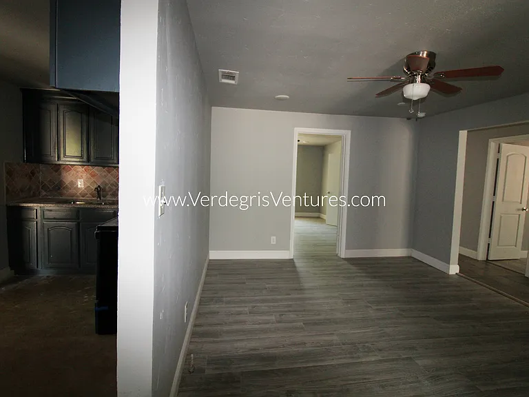 A spacious dining room sits at the very center of the home, serving as a natural hub between the kitchen and bedrooms. It features a ceiling fan and also functions as a convenient hallway connecting the main living areas