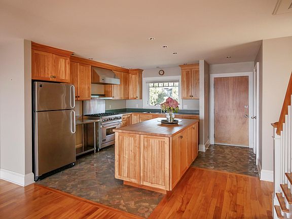 Large kitchen with butcher block island. Stainless steel appliances. Front entry shown.