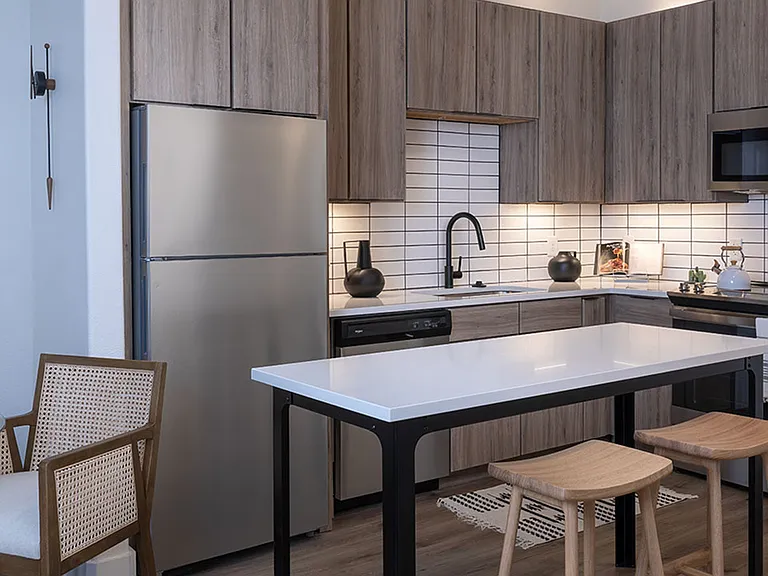 Apartment kitchen with stainless steel appliances, quartz countertops and wood-style flooring.